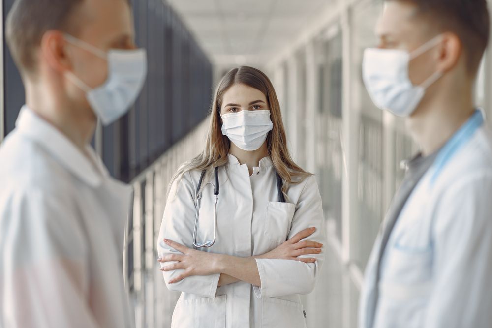 Clinicians in masks standing together in a bright hallway