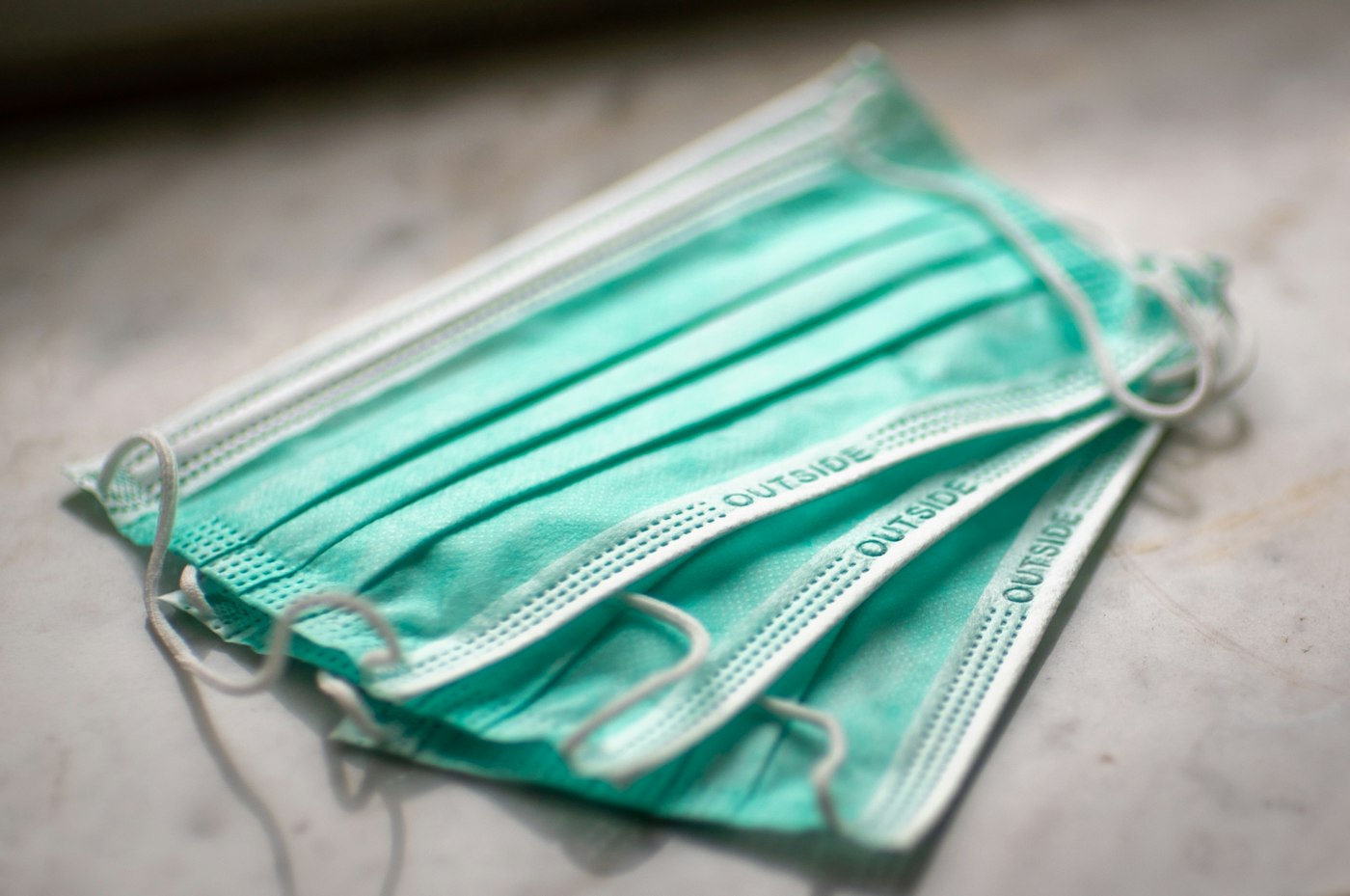A stack of soft green face masks on a stone surface